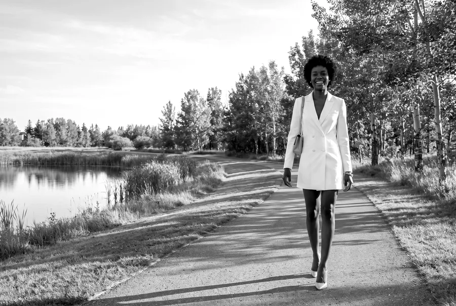 Black-and-white generated image: the guide's character walks along a paved trail by a pond and aspen trees in a city park.